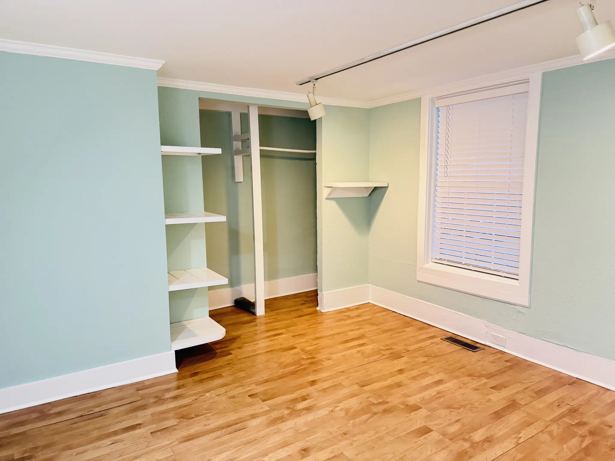 Room painted mint green with white trim and built-in shelves